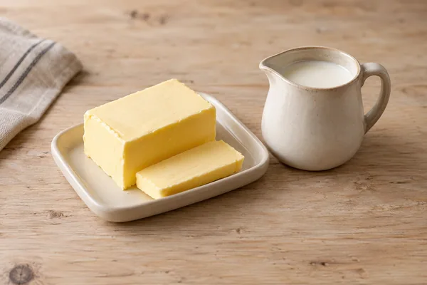 Butter auf einer kleinen Schale neben einem Krüglein mit Rahm